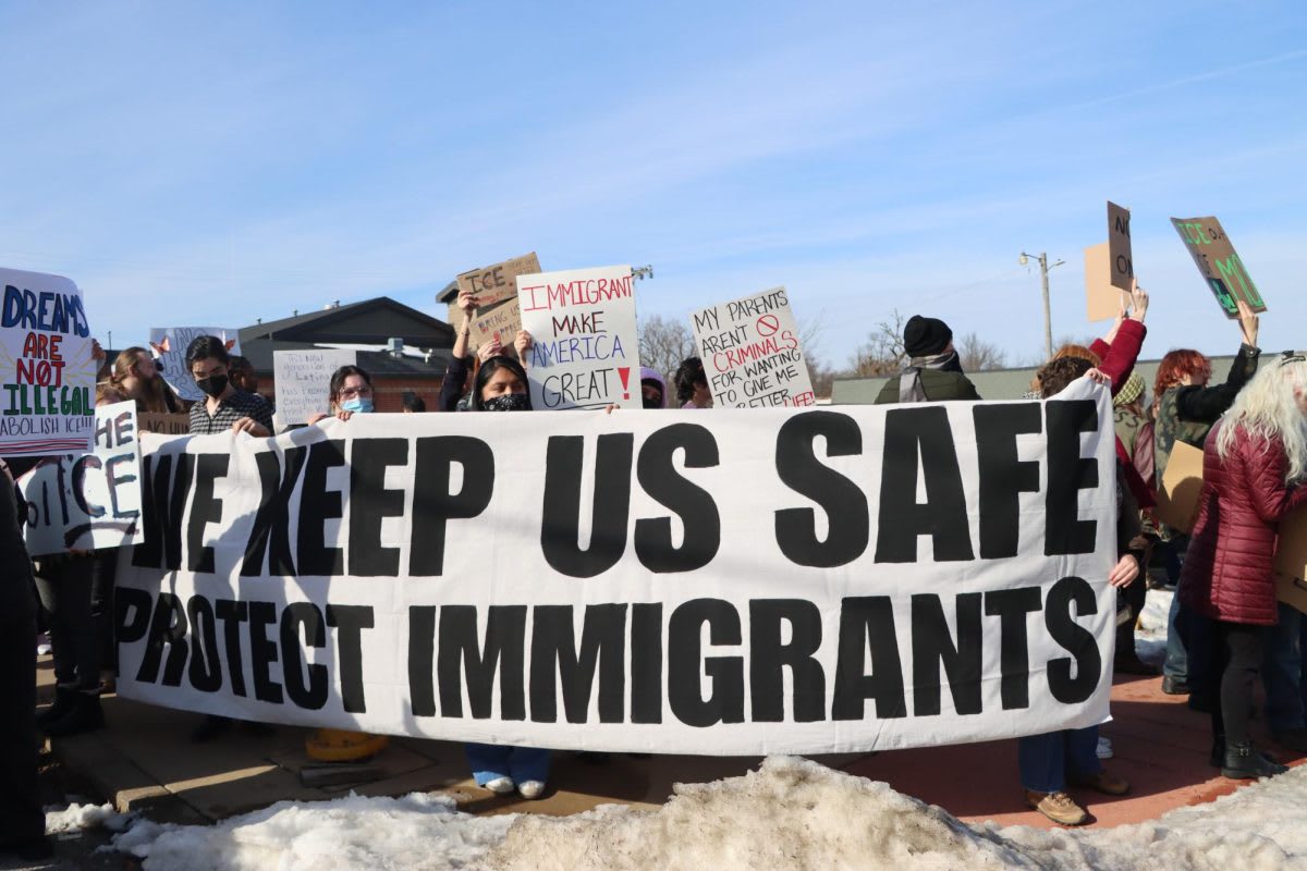 Community protest with 'We Keep Us Safe' banner supporting immigrants
